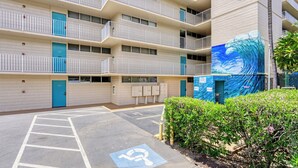 A multi-story hotel with a parking lot and a mural on the side. - Kamaole Nalu 403 - Ocean View - New DESIGNER Remodel wA/C (Kihei)