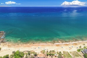 Ein Strand mit klarem Wasser, sandigem Ufer und Palmen.