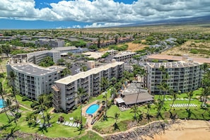 A resort with multiple buildings, a swimming pool, and a beach area. - Kamaole Nalu 403 - Ocean View - New DESIGNER Remodel wA/C (Kihei)