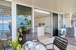 Ein Balkon mit Essplatz, einschließlich Stühle, Tisch und einem Blumenstrauß.