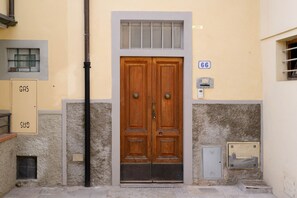 A double wooden door with a small window above it, a gas meter to the left, and a number '66' sign to the right. - Cozynest in Florence  (Firenze)