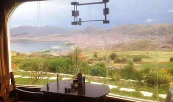 Una mesa con vista a un paisaje urbano, montañas y un cuerpo de agua.