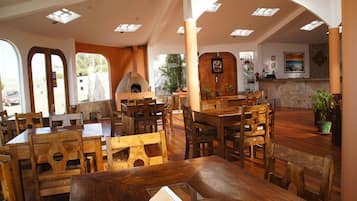 Un ristorante con arredi in legno, un camino in pietra e vista sull'esterno.