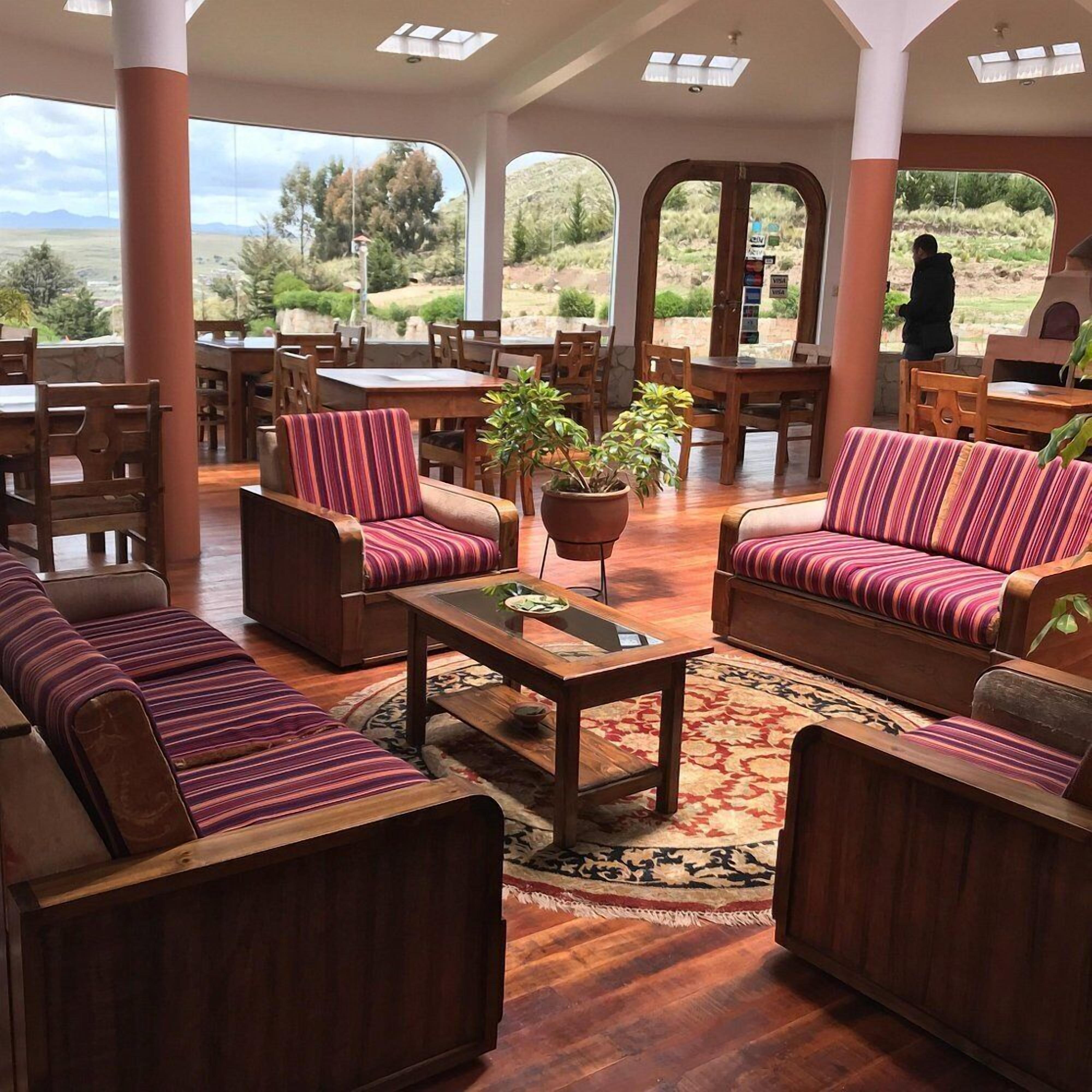A spacious indoor area with wooden furniture, including sofas and chairs, a coffee table, and a potted plant.