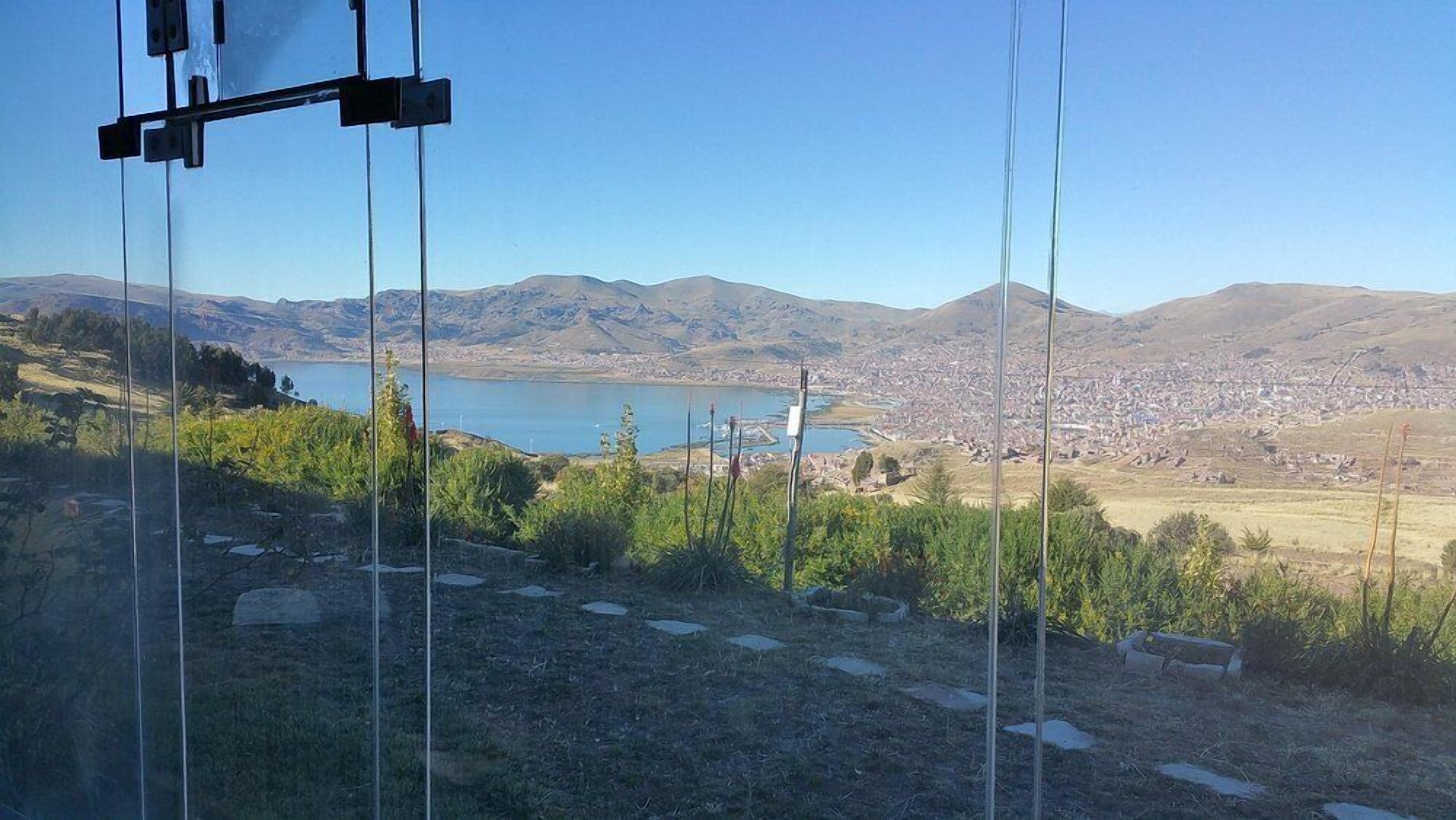 Een uitzicht op een meer met bergen op de achtergrond en een stadsgezicht.