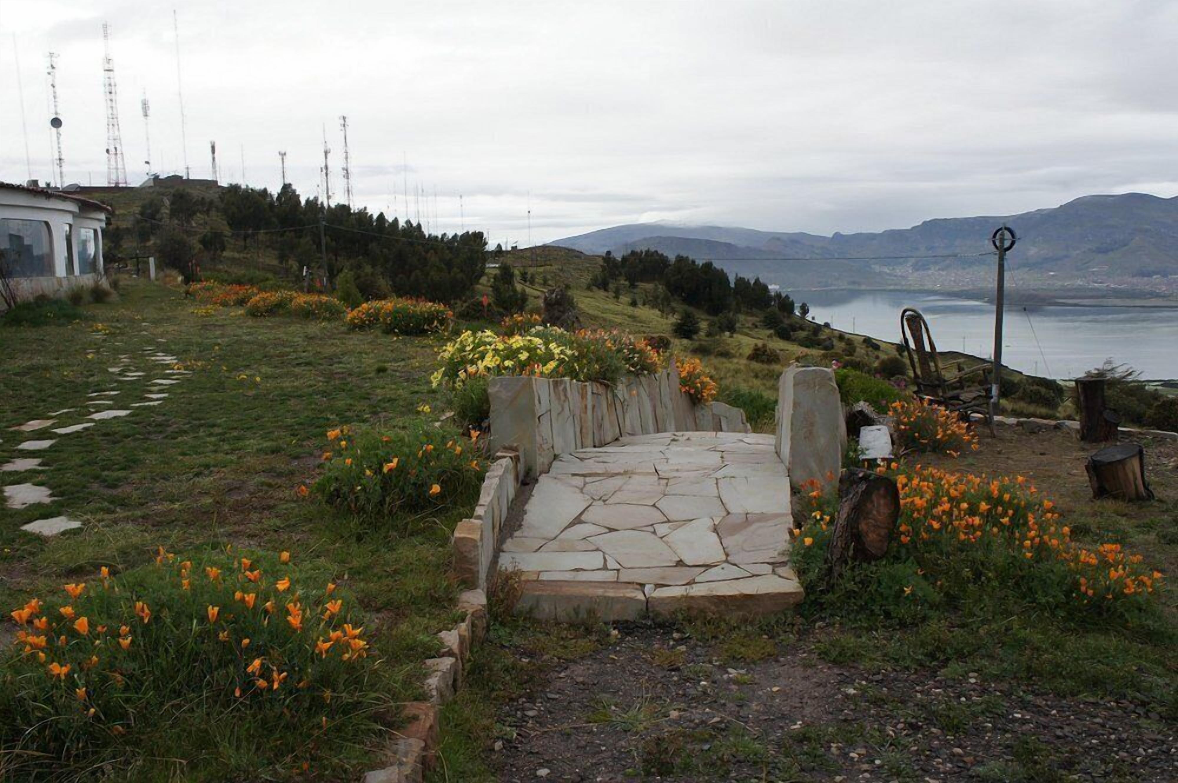 A stone pathway leading to a seating area with a view of a lake and mountains.