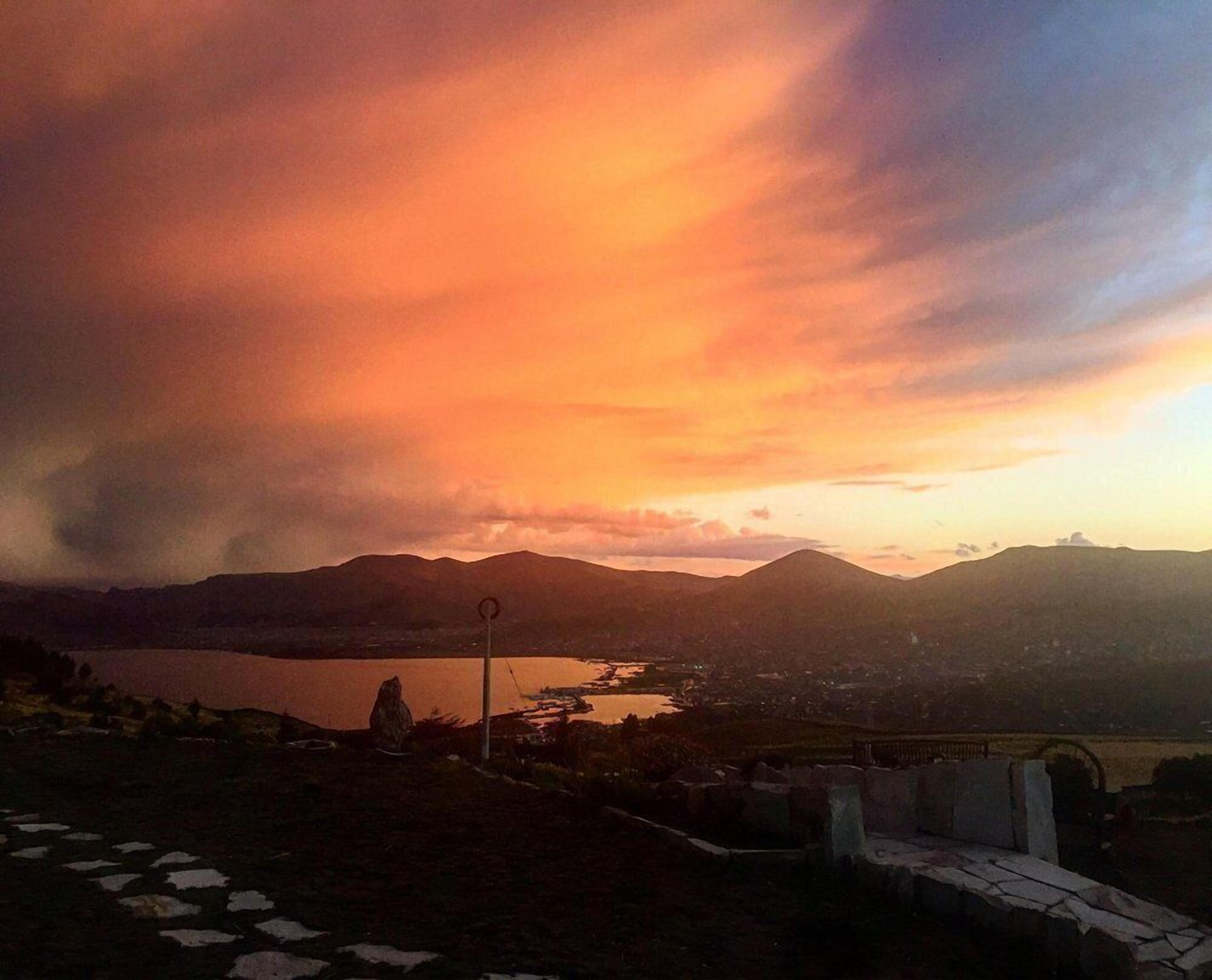 Tramonto su un paesaggio montuoso con un lago e un ponte.