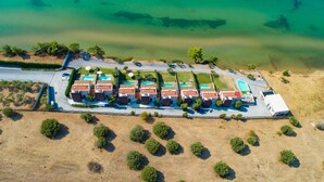 An aerial view of a coastal hotel with multiple buildings, a swimming pool, and a beach area. - Kalma Villa Tria in Moudania (Nea Propontida)