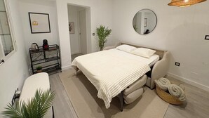 Ein Schlafzimmer mit Bett, Nachttisch, Spiegel und einer Pendelleuchte.