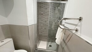 Ein kleines Badezimmer mit Toilette, einer Duschkabine und einem Handtuchhalter.