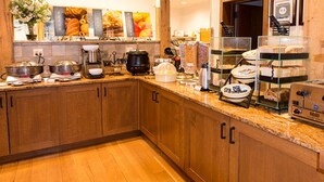Eine Küche mit Holdelementen, einer Granitabdeckung und verschiedenen Geräten, darunter eine Kaffeemaschine, ein Wasserkocher und eine Speisenauslage.