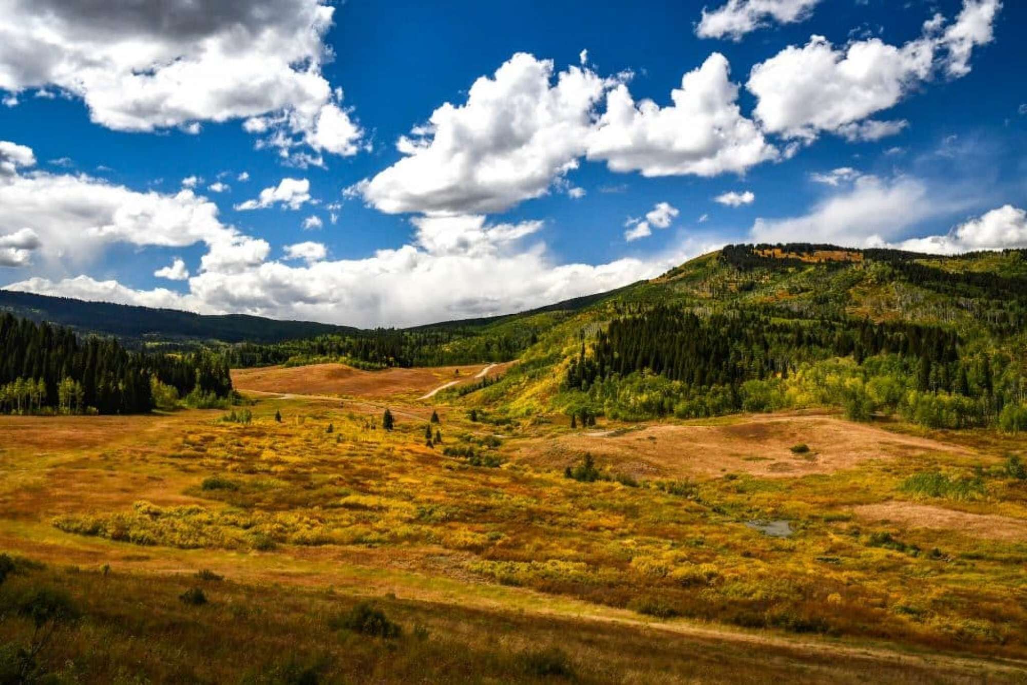 A panoramic view of a mountainous landscape with a clear sky and scattered clouds.