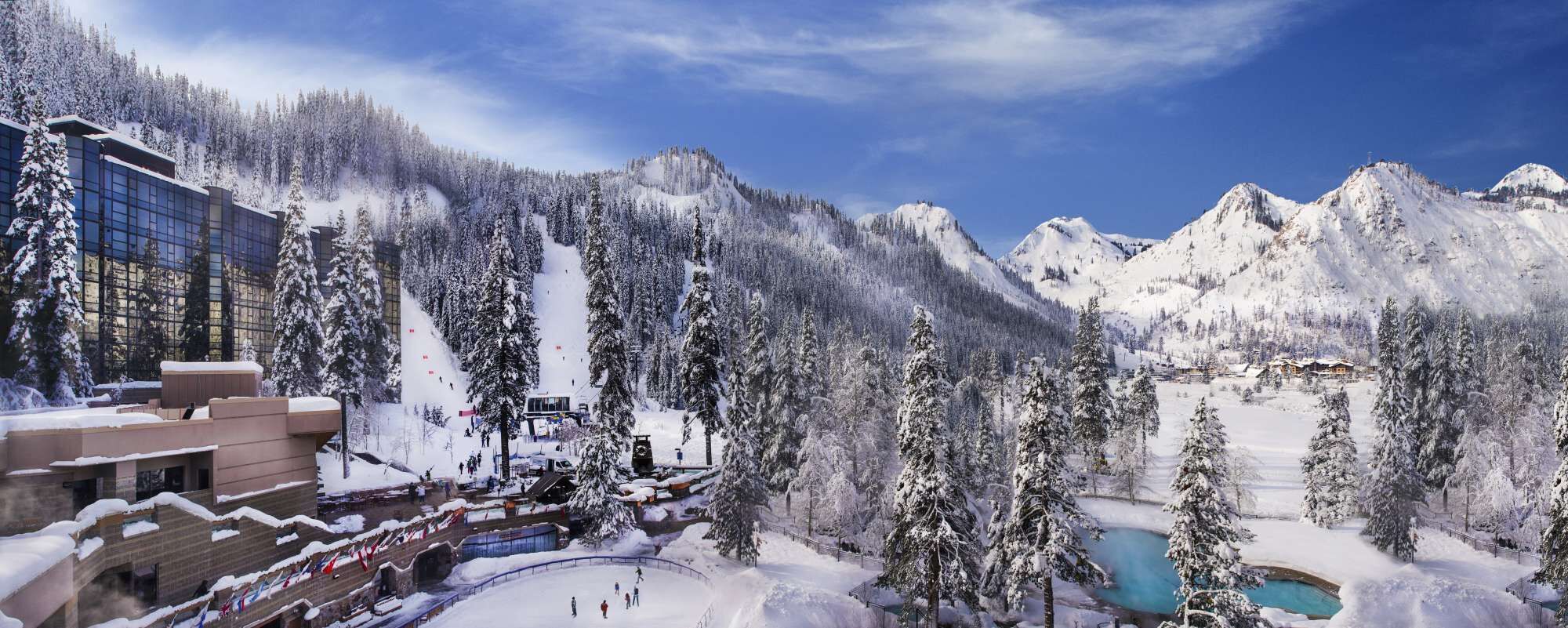 A snow-covered mountain resort with a ski lift, a pool, and a building with large windows.