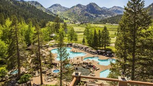 Un resort con varias piscinas, un campo de golf y vistas a las montañas.