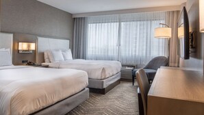 A hotel room with two beds, a desk, and a chair. There is a large window with sheer curtains, a wall-mounted lamp, and a flat-screen TV. - Near South Coast Plaza | Pool, Dining + Spa (Santa Ana)
