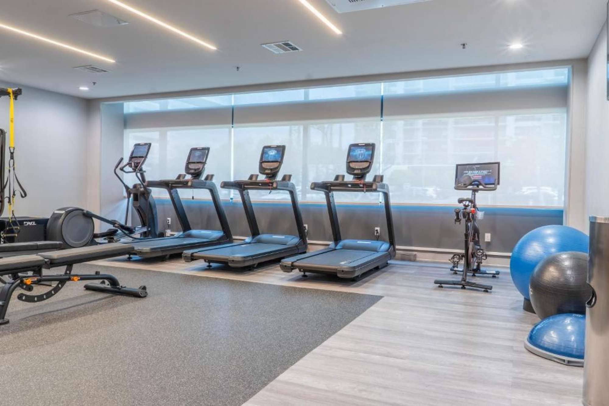 Un gimnasio con cintas de correr, una bicicleta estática y pelotas de ejercicio.