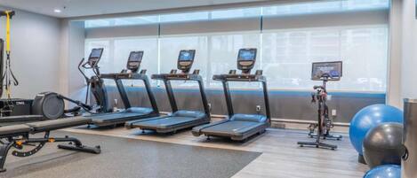 Un gimnasio con cintas de correr, una bicicleta estática y pelotas de ejercicio.