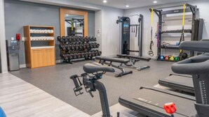 A gym with weightlifting equipment, treadmills, and a mirrored wall. - Near South Coast Plaza | Pool, Dining + Spa (Santa Ana)