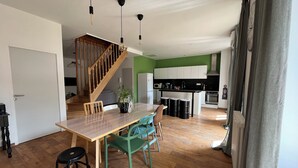 A modern kitchen with white cabinets, a black countertop, and a built-in oven. There is a wooden staircase leading to another level. - Duplex apartment in the center of Montignac-Lascaux (Montignac-Lascaux)