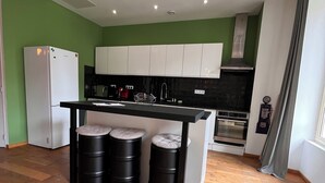 A modern kitchen with green walls, white cabinets, and a wooden floor. - Duplex apartment in the center of Montignac-Lascaux (Montignac-Lascaux)