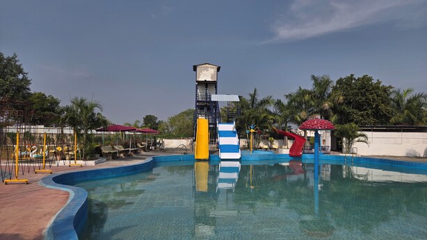 A swimming pool with a slide and a tower structure. - SHYAM RESORT (Khandwa)