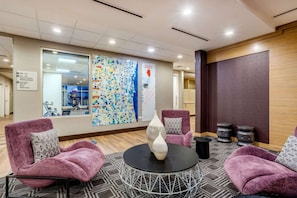 A hotel lobby with purple armchairs, a round table with vases, a map on the wall, and a wooden panel on the right. - Near Six Flags | Free Breakfast & Parking. Kitchen (Waukegan)