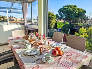 A breakfast table set with various food items and a view of a garden. - FeWo C-01 by Interhome (Colà)
