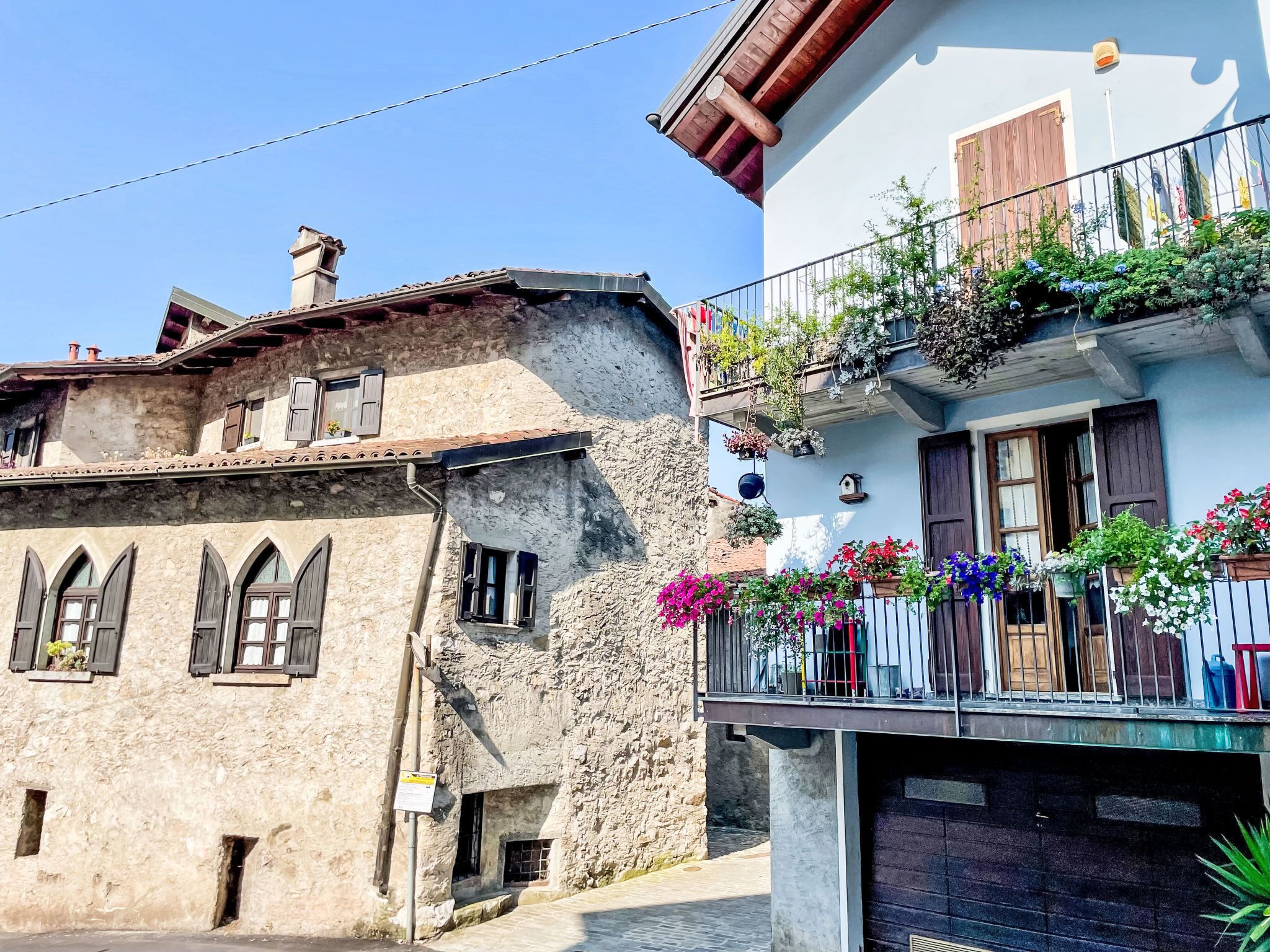 A traditional stone building with arched windows and a balcony with hanging flower baskets.