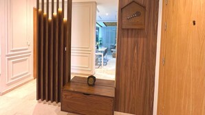 A hallway with a wooden partition, a small wooden chest, and a door with a guitar decoration. - 3 bedrooms apartment in secure Résidence (Casablanca)