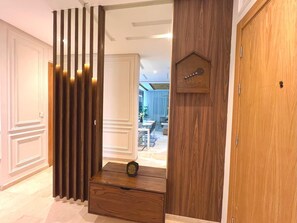 A hallway with a wooden partition, a small wooden chest, and a door with a guitar decoration. - 3 bedrooms apartment in secure Résidence (Casablanca)