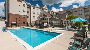Un hotel con piscina, mobiliario exterior y un patio cubierto.