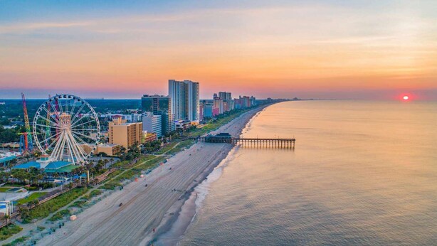 A coastal cityscape with a beach, a Ferris wheel, and high-rise buildings during sunset. - 2 Bedroom Suite w/ Kitchen + Free Parking & Pool (Florence)