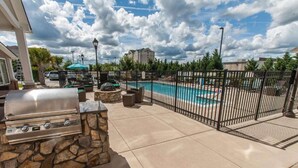 An outdoor patio with a stone barbecue, a pool, and a fence. - 2 Bedroom Suite w/ Kitchen + Free Parking & Pool (Florence)