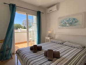 A hotel room with a bed, a nightstand, a painting, and a view through a sliding door. - Apartment in Nerja Near Burriana Beach (Nerja)
