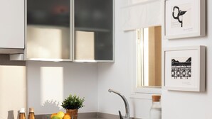 Een moderne keuken met witte kastjes, een roestvrijstalen spoelbak en een raam dat voor natuurlijk licht zorgt.