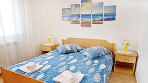 Ein Schlafzimmer mit einem Bett, zwei Nachttischen und einer Wand mit vier Bildern.