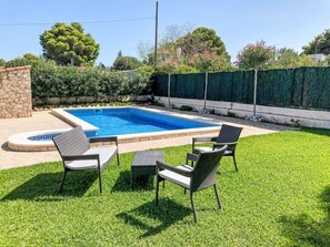 A swimming pool with a geometric tile border, surrounded by a well-maintained lawn and a hedge. - Casa Blumer by Interhome (L'Ametlla de Mar)