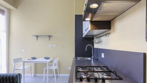 Uma cozinha compacta com fogão a gás, pia e um pequeno espaço de refeições com cadeiras e mesa.