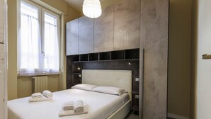 Um quarto moderno com uma cama grande, estantes embutidas e uma janela com cortinas leves.