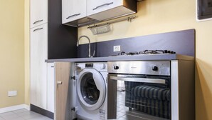 Cozinha compacta com máquina de lavar, forno e bancada pequena.