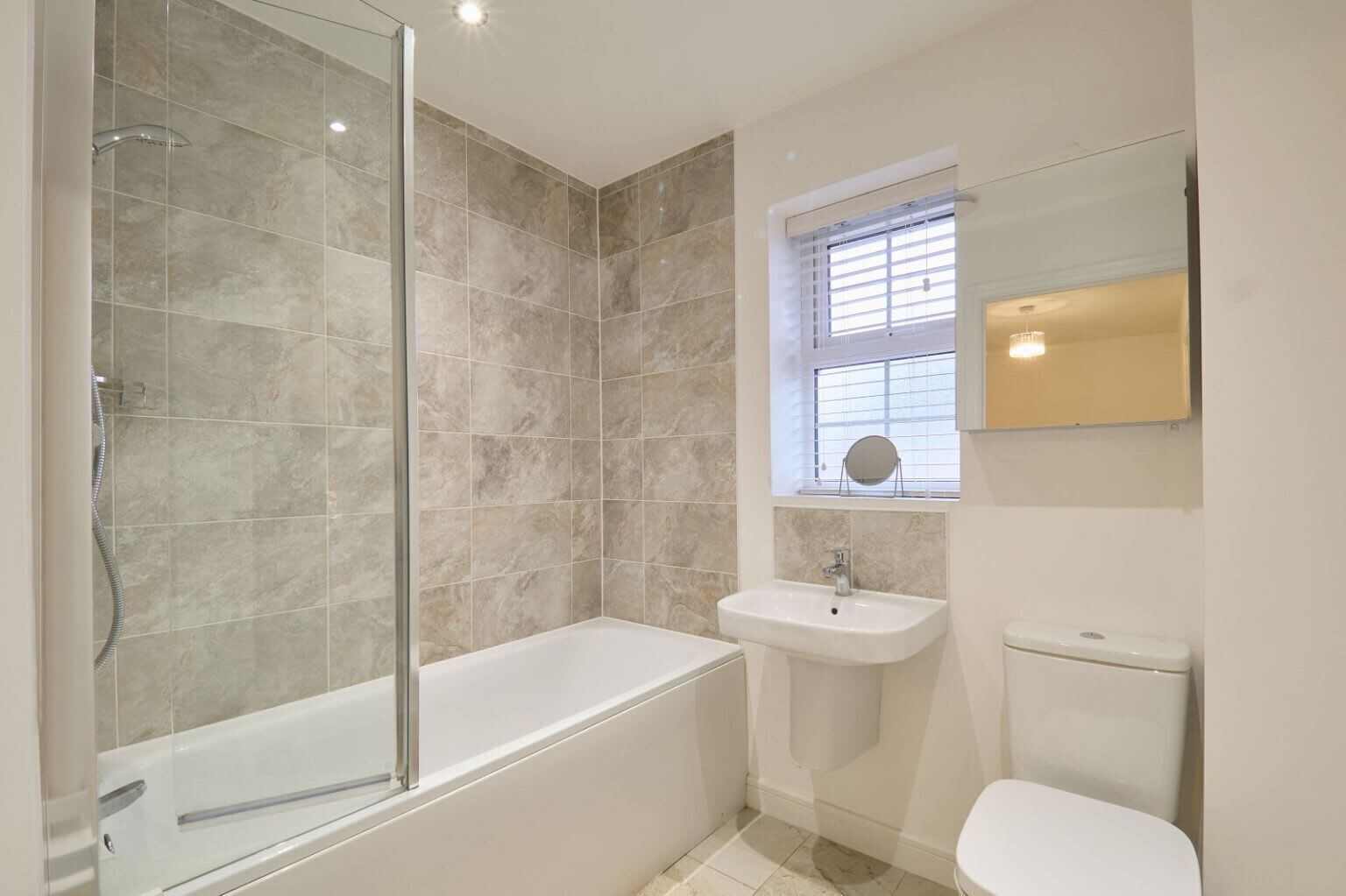A modern bathroom with a glass-enclosed shower, a standalone bathtub, a pedestal sink, and a toilet.