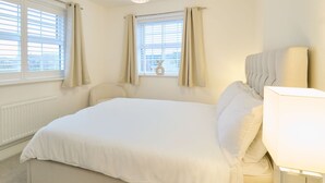 A spacious bedroom with a large bed, a bedside lamp, and a view of the city through the window. - Host and Stay The Cosy Corner (Canterbury)