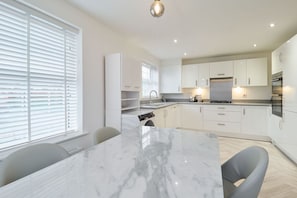 A modern kitchen with white cabinets, a marble countertop, and stainless steel appliances. - Host and Stay The Cosy Corner (Canterbury)