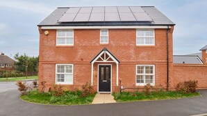 A two-story brick house with a black front door, white windows, and a small garden area with shrubs. - Host and Stay The Cosy Corner (Canterbury)
