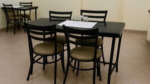 Een eethoek met een zwarte tafel en vier stoelen met bruine kussens.