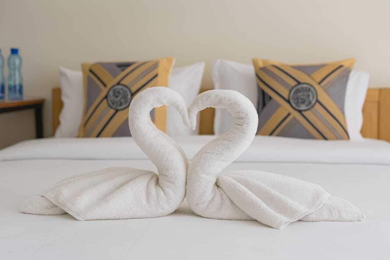 Un letto con biancheria bianca e due cuscini a motivi geometrici.