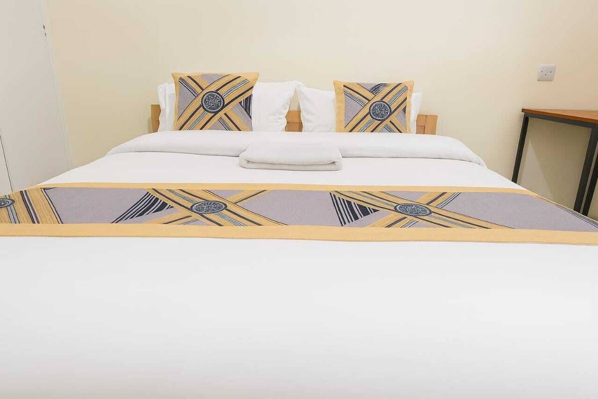 A neatly made bed with a patterned bedspread, white pillows, and a folded towel.