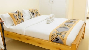 Een enkel bed met houten frame, witte beddengoed en gestreepte kussens.