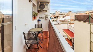A balcony with a table and chairs, a potted plant, and an air conditioning unit. - Apartment  by Interhome (St Antoni de Calonge)