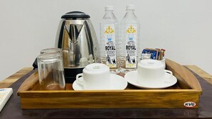 Een dienblad met een koffiezetapparaat, twee waterflessen, twee bekers en een pak tissues.